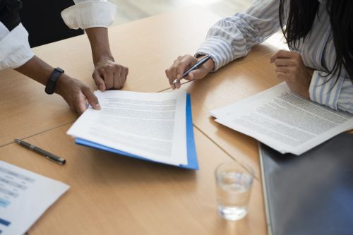Shot of documents and female hands signing contract