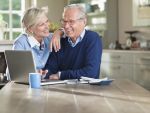 Couple using laptop at kitchen table
